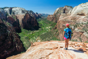 Young woman is looking at the magnificent view from Angel's landing in Zion National park. Travel and adventure concept.