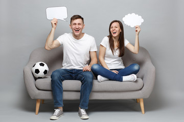 Laughing couple woman man football fans cheer up support favorite team with soccer ball holding empty blank Say cloud speech bubble isolated on grey background. Sport family leisure lifestyle concept.