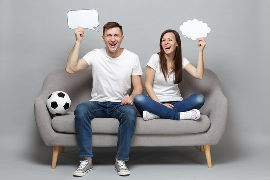 Laughing couple woman man football fans cheer up support favorite team with soccer ball holding empty blank Say cloud speech bubble isolated on grey background. Sport family leisure lifestyle concept.