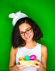 Cute teen girl with Bunny Ears and Christmas eggs on a green background.