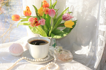 A cup of coffee and flowers on a light background, wishes of good morning and good day, a cozy home