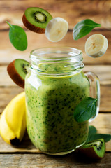 Spinach banana kiwi smoothie on a dark wood background