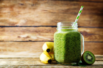 Spinach banana kiwi smoothie on a dark wood background