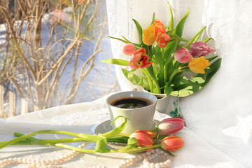 A cup of coffee and flowers on a light background, wishes of good morning and good day, a cozy home