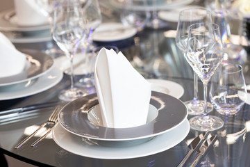 Detail of black and white modern banquet setting on glass table. Blurry background.