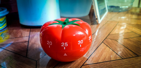 Pomodoro timer on the talble - mechanical tomato shaped kitchen timer for cooking or studying.