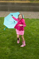 cute young girl playing in the rain with umbrella