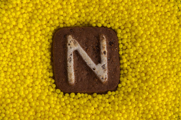 letters of the English alphabet on the background of yellow sweet balls