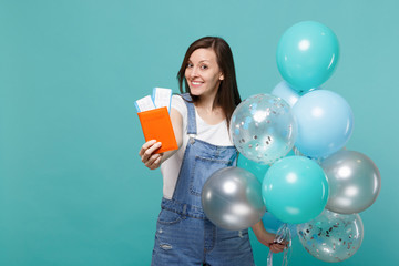 Pretty young woman in denim clothes holding passport boarding pass ticket celebrating with colorful...