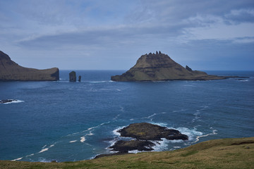 Epic colorful landscape of wild nordic or scandinavian coastline without trees with atlantic ocean, mountains, high cliffs in island Vagar in Faroe island taken in sunny, cloudy and windy summer day. 