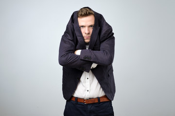 Young man in too big suit. He is offended and looking stressed.