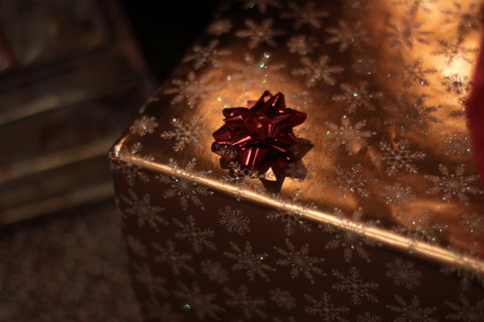 Close Up Of Gold Wrapped Christmas Present With A Red Bow 