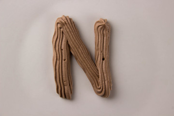 Sweet chocolate letter N drawn with whipped cream on a white plate