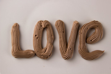 Sweet chocolate lettering LOVE drawn with whipped cream on a white plate