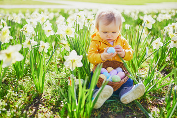 Cute little one year old girl playing egg hunt on Easter
