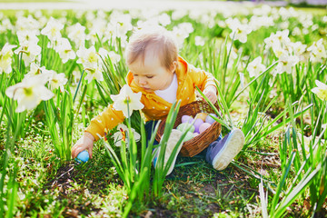 Cute little one year old girl playing egg hunt on Easter