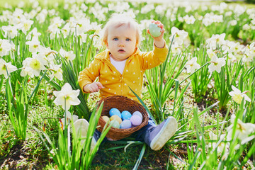 Cute little one year old girl playing egg hunt on Easter