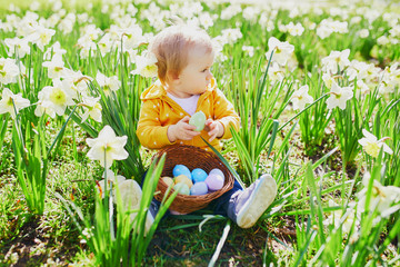 Cute little one year old girl playing egg hunt on Easter