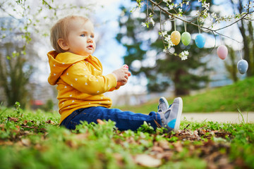Cute little one year old girl playing egg hunt on Easter