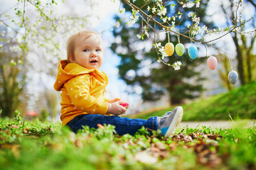 Cute little one year old girl playing egg hunt on Easter