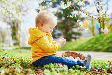 Cute little one year old girl playing egg hunt on Easter