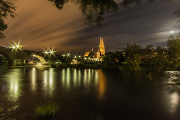 Fototapeta na wymiar A night long exposure of the cathedral Dom St Peter with an old stone bridge along the Danube