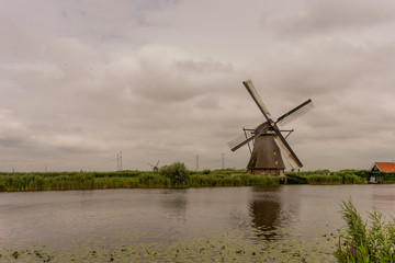 Naklejka premium Netherlands, Rotterdam, Kinderdijk, heritage windmill above lush green grass along a canal