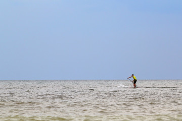 Athletic man paddling on stand up paddle board (paddleboard, SUP) on sea. Stand up paddle boarding...