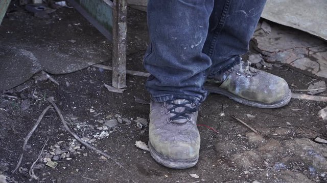 Worker in old shoes at the factory close-up