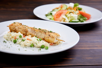 chicken kebab with rice and vegetables on the wooden background