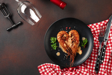 Romantic dinner with heart-shaped shrimps and wine on a brown background. Top view with copy space