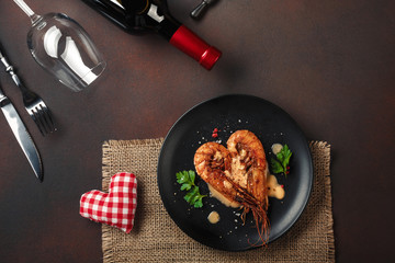 Romantic dinner with heart-shaped shrimps and wine on a brown background. Top view with copy space