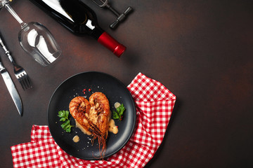 Romantic dinner with heart-shaped shrimps and wine on a brown background. Top view with copy space