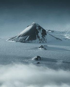 Large black hill in the center of a flat snowy landscape