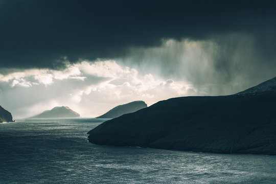 Rain falling from distant clouds over water in the Faroe Islands