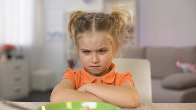 Girl refusing eat breakfast oatmeal, pushing bowl away, healthy child nutrition