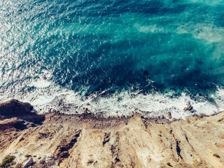 Fototapeta na wymiar Aerial top view of azure sea water with waves at sand coastline, beautiful summer tropical ocean background with copy space