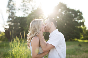 Romantic portrait of a newly engaged couple kissing in sunshine