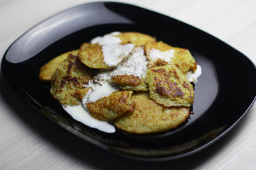 Potato pancakes with sour cream on a black plate