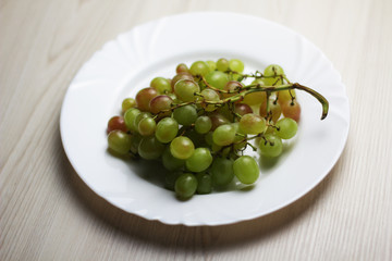 Bunch of white grapes on the white plate
