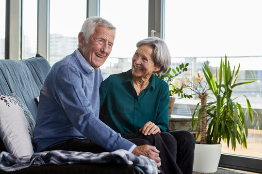 Laughing senior couple sitting together on couch