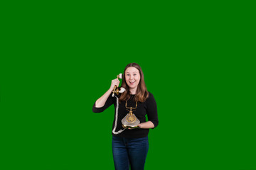 Young female holding a old corded telephone receiver to her ear on green screen background