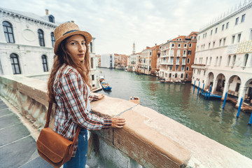 Fototapeta na wymiar Woman in the Venice, standing on the bridge over the grand canal while on sightseeing in a foreign city. Discovery the Venice adventure.