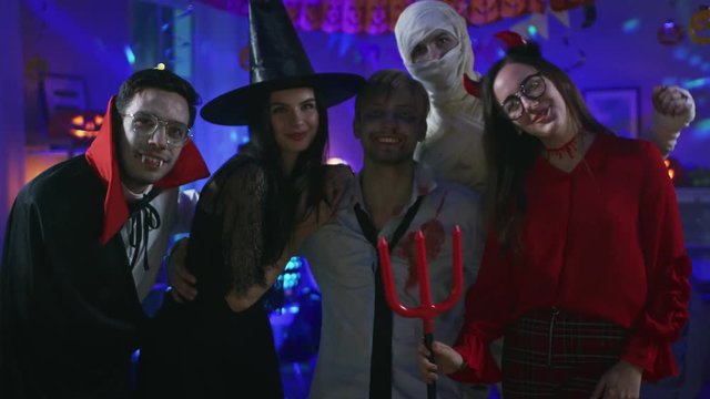 Halloween Costume Party:Brain Dead Zombie, Blood Thirsty Dracula, Bandaged Mummy Beautiful Witch and Seductive She Devil Posing for Group Selfie Looking at Camera. Monsters Have Fun in Decorated Room