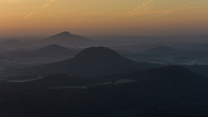 Landscape full of forest before sunrise with morning fog. Forest landscape where peaks of hills are above the fog.