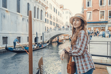 Fototapeta na wymiar Woman waiting for gondolas near canal in Venice