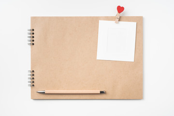 kraft notebook, photo frame and pen on white