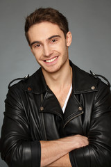 What a hottie. Vertical studio portrait of a handsome biker man looking to the camera smiling happily