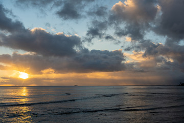 Obraz premium Beautiful sunset on the coast of Oahu, Hawaii. A small boat can be seen in the distance. 