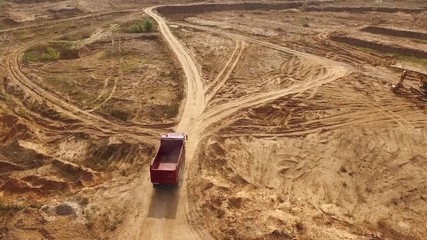 Aerial view of the empty large red truck moving on a sandy track for the sand in desert or dunes. Beautiful view from above.
